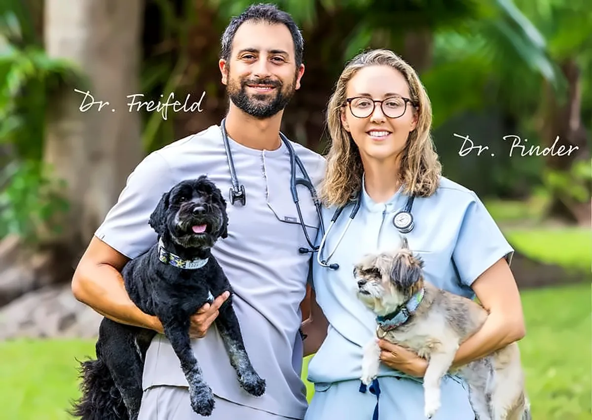 Dr. Freifeld and Dr. Pinder holding their two dogs